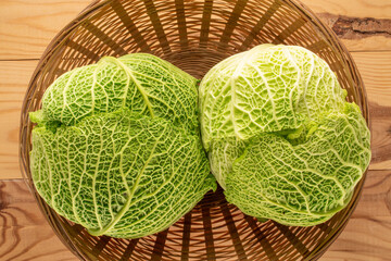 Two bales of ripe Savoy cabbage in a straw dish, macro, top view.