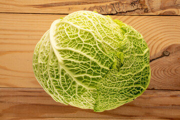 One cabbage of organic Savoy cabbage on a wooden table , macro, top view.