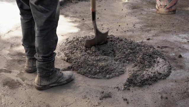Worker mixing up cement with a shovel 