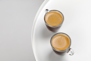 Two glasses coffee cup with espresso in morning on white table. Aroma, ristretto. Mug of coffee. Glass. Close up, top view