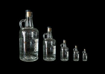 Glass vodka bottles in a row by size on a black background