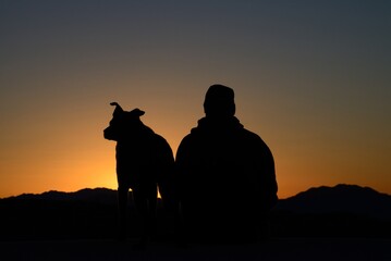 Obraz na płótnie Canvas Dog and master watching sunrise, Mojave Desert, California, USA, MR