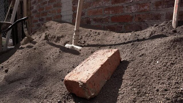 Old hammer and brick on the soil 
