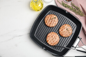 Grill pan with tasty fried hamburger patties and seasonings on white marble table, flat lay. Space for text