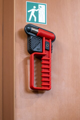 Ein Notfall Hammer in rot an seiner Halterung darüber ein Hinweis Schild in grün auf einem...