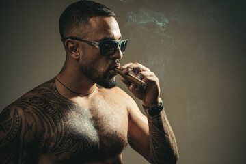 Brutal angry gang man lifestyle, serious handsome guy smoking cigar.