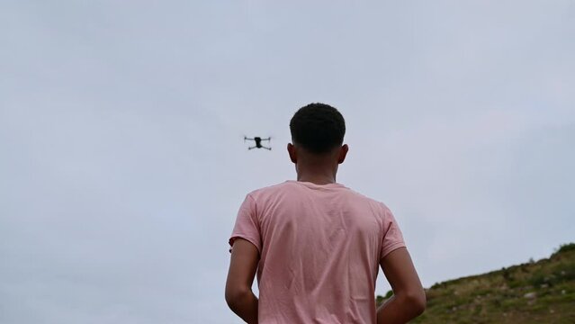 Rear view of teenager seen flying a drone