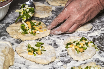 Womens hands mold pies stuffed with onions, eggs and greens