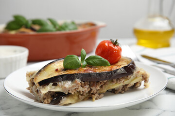 Plate of delicious eggplant lasagna served on white marble table, closeup