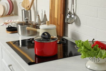 Red pot on electric stove in kitchen. Cooking utensil