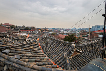 Fototapeta premium View above old buildings with traditional Korean roof tiles at Bukchon Hanok Village in Seoul, South Korea.