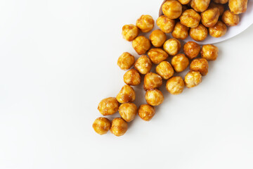 Scattered hazelnuts in caramel on a white background. Very tasty and healthy and high-calorie dessert.