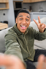 Great selfie. Multiracial young guy gesturing to the smartphone camera, while making funny photos...