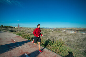 Series Running man with red shoe. Detail of the legs in wide angle of a young man running in the street of his neighborhood to exercise and be healthy driving away stress