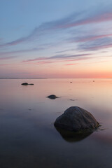 Fototapeta na wymiar Sunset with a beutiful pink colored clouds. Long exposure photo of rocky sea shore in the evening