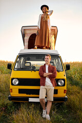 Hipster couple ready for roadtrip on yellow oldtimer mini van transport. Travel lifestyle concept...