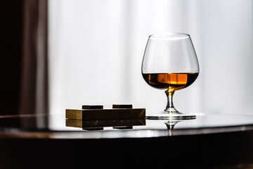 Natural cognac in a glass on a dark background on a black mirror surface, sweet sticks are falling-2.