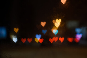 Night city lighting in the shape of hearts through wet car windshield. Bokeh. Valentine's Day, Love, Romance concept.