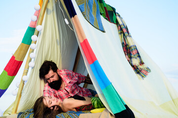 Romantic couple camping on spring landscape. Adventure for young lovers campers in tent on nature. Hipster couple tender kissing in camp tent.