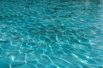 blue water surface in the pool reflects sun glare