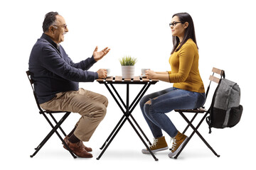 Mature man and a young female sitting at a cafe table and talking