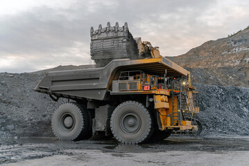 A heavy excavator loads ore into a dump truck at an open-pit gold mine.