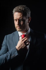 Portrait shot of a middle aged businessman in suit at dark black background. People, business, fashion and clothing concept, closeup of man in suit and necktie.