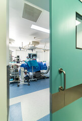 View from the door at the group of neurosurgeons in operating room with surgery equipment. Doctors using hi-tech equipment. Modern medical background.