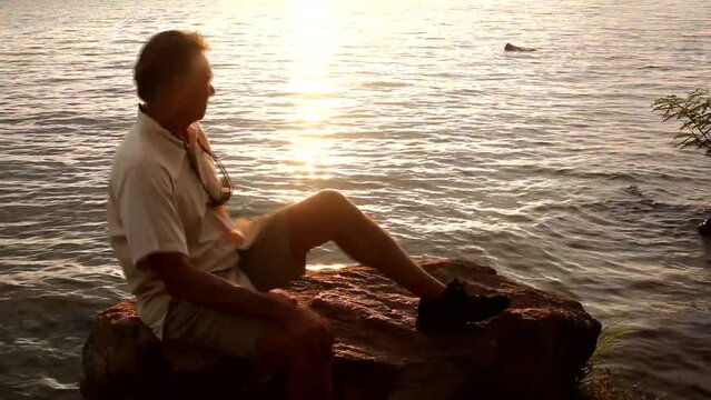 Man man sitting on s big rock on Lago Paranoa in Lago Norte Brasilia, Brazil