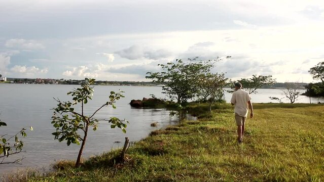 Mature Man walking along Lago Paranoa at Parque das Garcas in Lago Norte Brasilia, Brazil