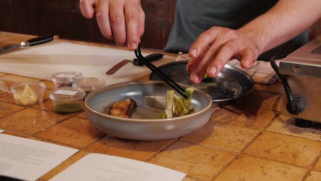 The chef on the stream prepares a dish of fried fish with broccoli and sauce