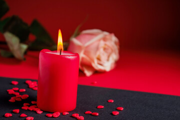 A burning red candle and a rose. Valentine's Day concept.