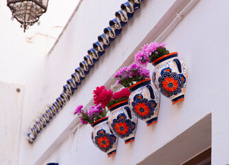 multicolored pots of flowers hanging on walls of a typical village