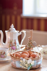 
a basket of eggs with a teapot and a cup on the table