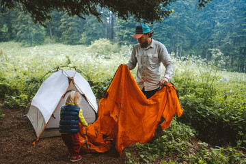 Father and daughter are setting up camping tent family vacations travel lifestyle hiking outdoor in...