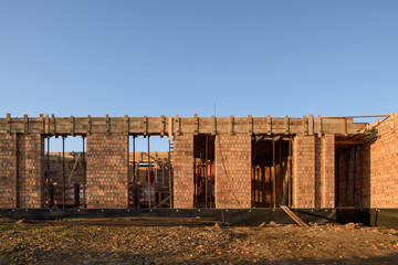 Brick house under construction. Elements of wooden formwork for pouring concrete at a construction site. Mounting telescopic stand for the installation of formwork beams.
Monolithic building.