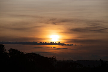 Sunrise on the horizon with orange sky and sparse clouds