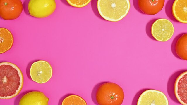 Fresh ripe sliced citrus fruits make frame border on vibrant pink theme. Stop motion flat lay