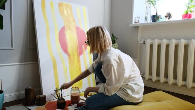 Young woman artist is painting at home in a creative studio setting. 