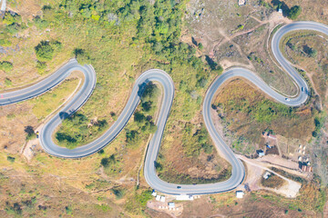 Aerial view of cars driving on curved, zigzag curve road or street on mountain hill with green...