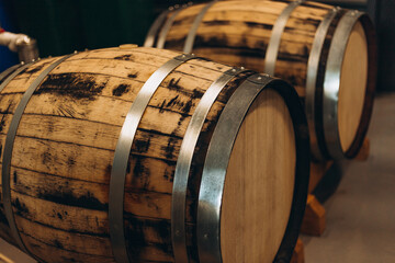 Wooden beer or wine barrels with iron rings in the cellar. Modern Factory. Brewery. Rows of wine barrels in an aging cellar