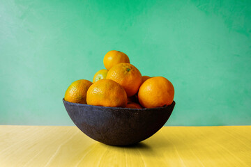 Tangerines in a bowl. Oranges. Green background. Ceramic fruit bowl