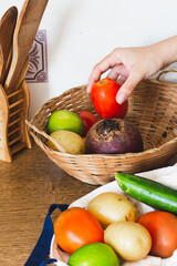 Straw basket with vegetables on wooden background.