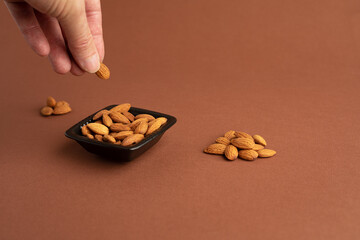 Mano agarra almendras de recipiente horizontal