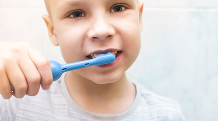 Boy brushing his teeth with a blue electronic toothbrush