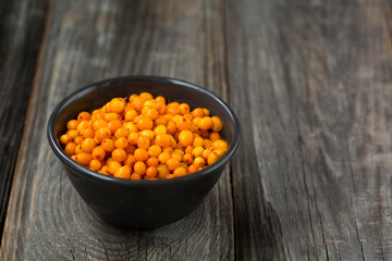 orange sea buckthorn berries on wooden table. copy space