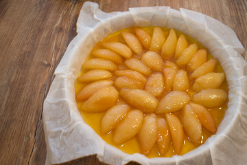 Pear tatin tart before cooking. Top view on a wooden table.