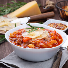Delicious minestrone soup served with crispy bread, on wooden background, square format