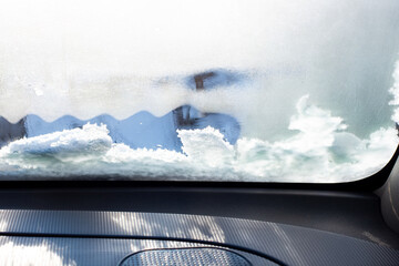 Frozen windshield in the car, view from the passenger compartment. Warming up the car in winter