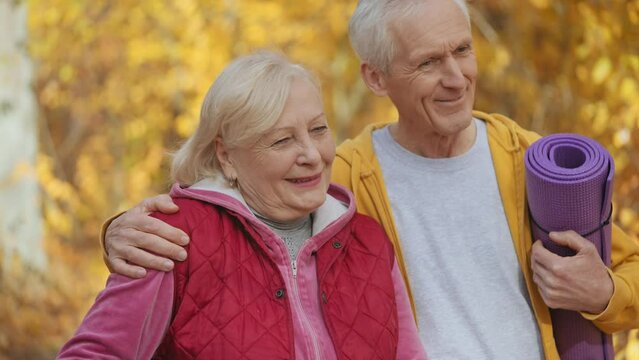 Cheerful and healthy mature couple holding fitness mats, exercising together